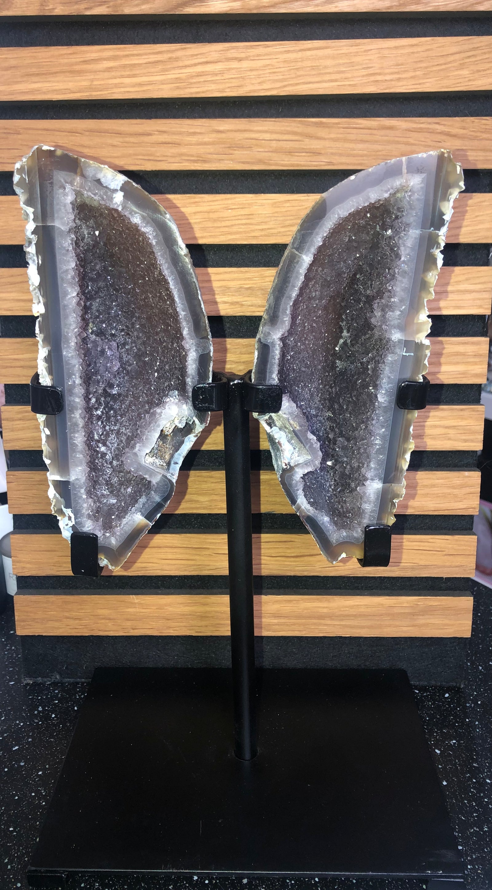 Agate and Amethyst geode pair mounted on a black metal stand,