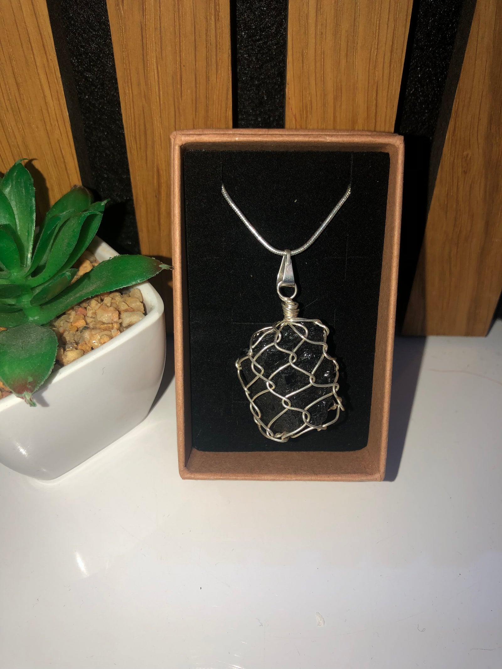 Raw tourmaline in caged pendant