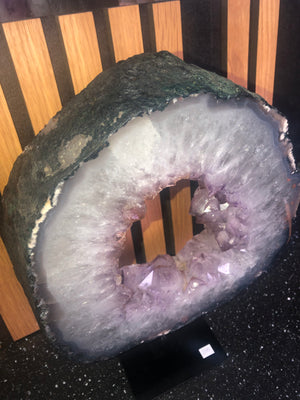 amethyst crystal portal mounted on a black metal stand.
